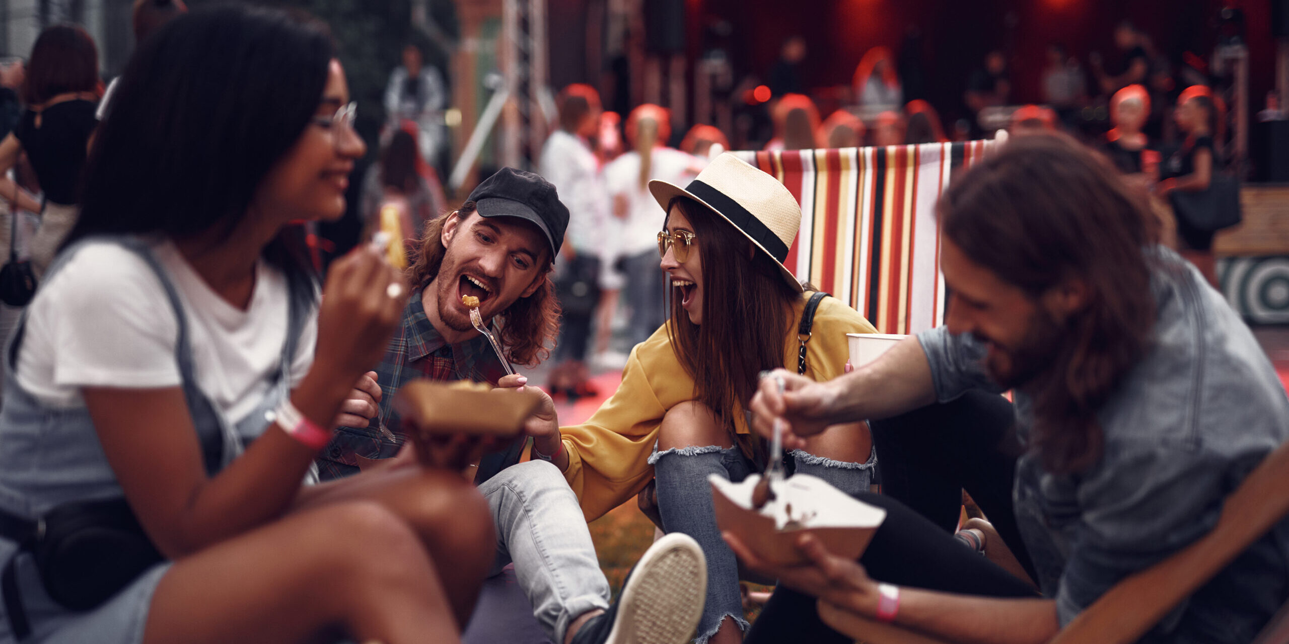 Young people enjoying meal and having fun during outdoor concert