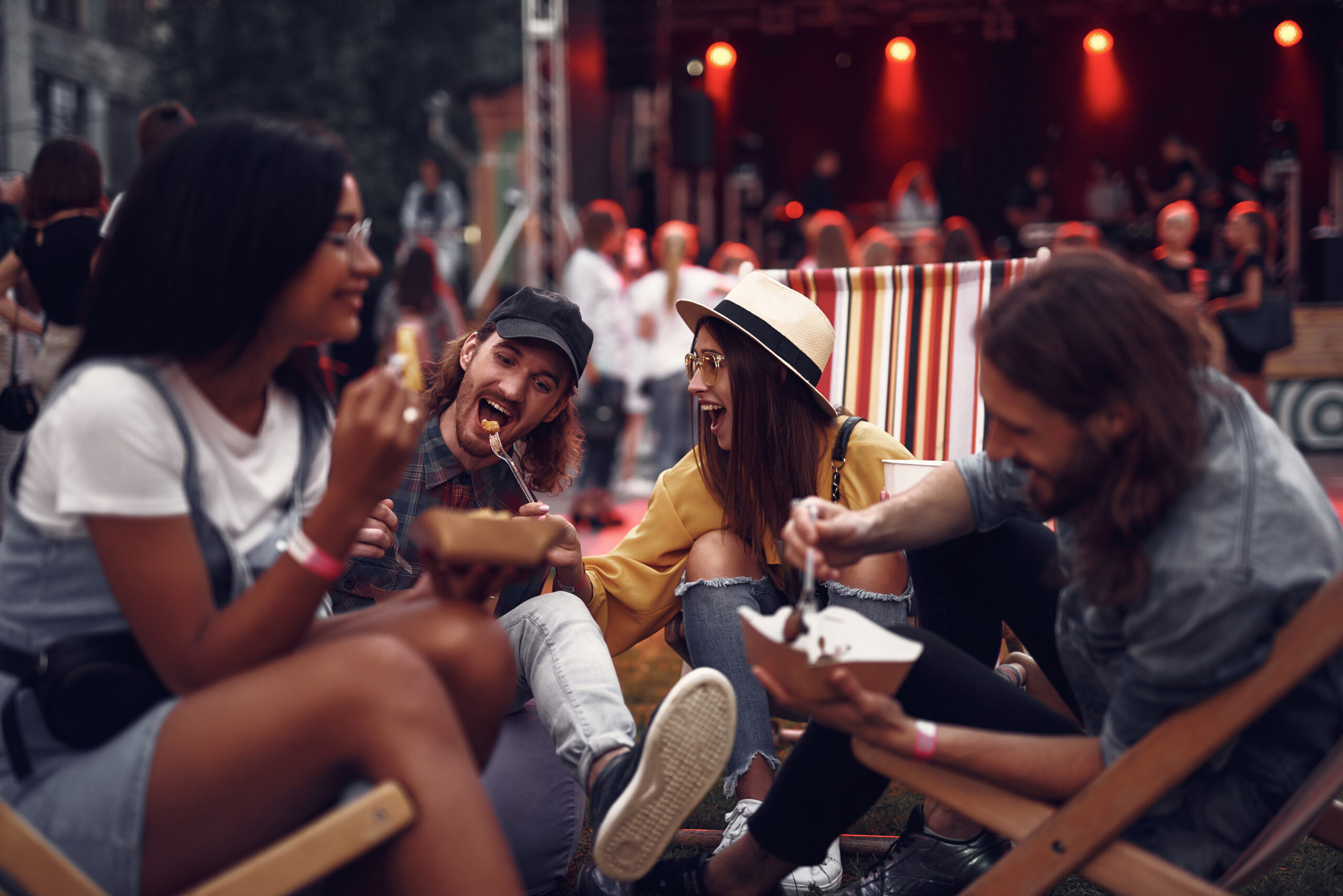 Young people enjoying meal and having fun during outdoor concert